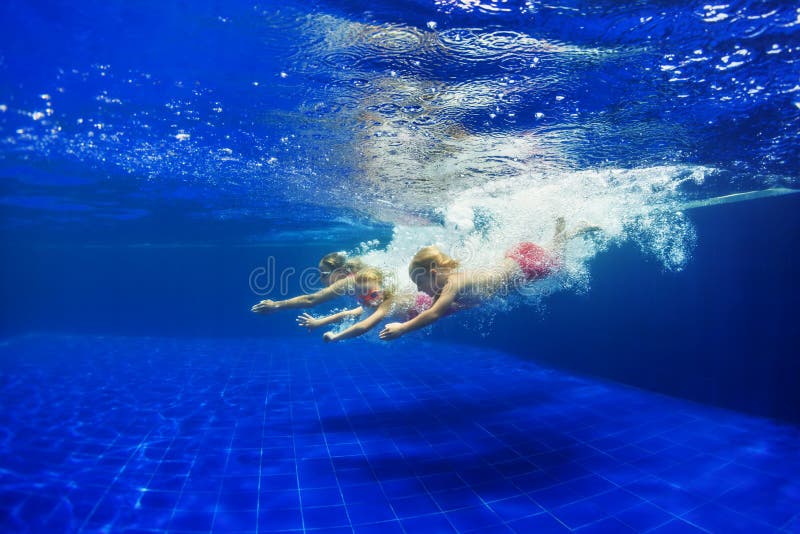 Kids with mother dive in swimming pool