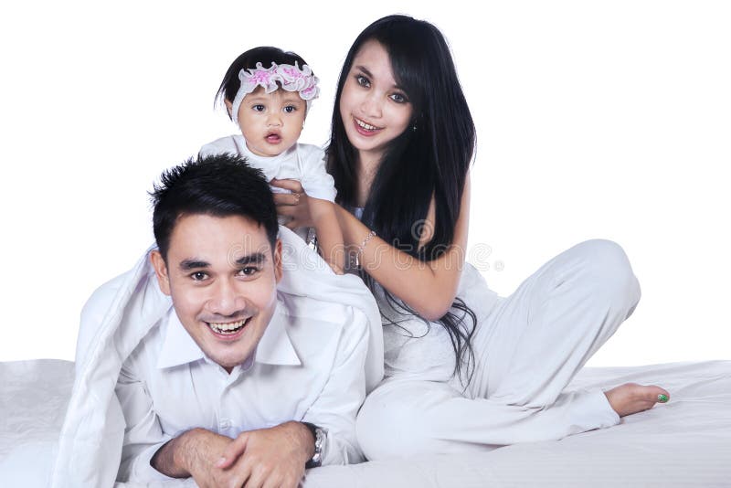 Happy family playing with their baby on the bed isolated over white background