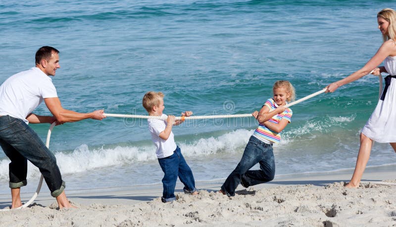 Happy family playing tug of war at the beach