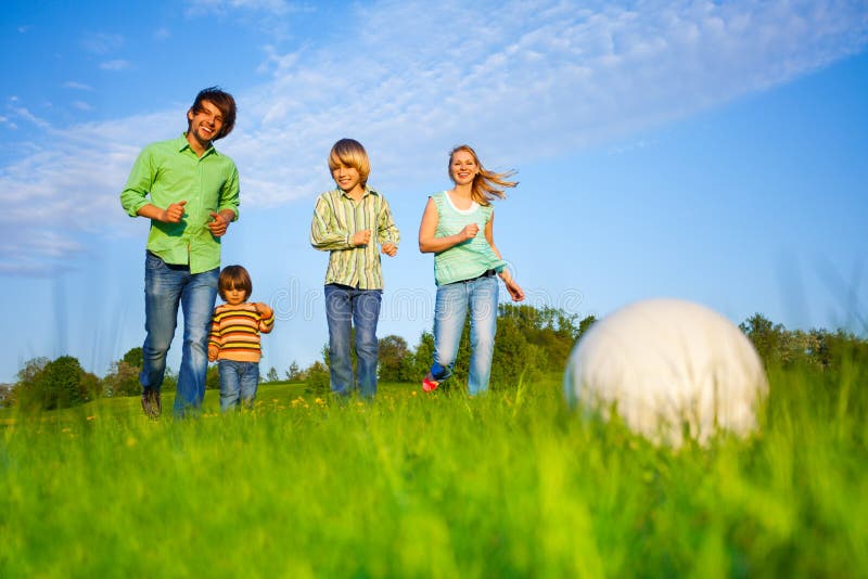 Happy family plays football together in park in summer. Happy family plays football together in park in summer