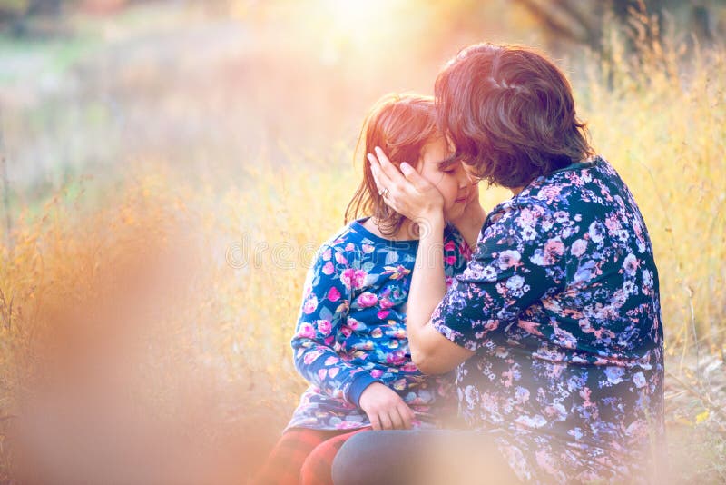 Happy family. Pregnant mom and little daughter hugging and kissing at sunset in autumn in forest. Laughter, happiness and fun