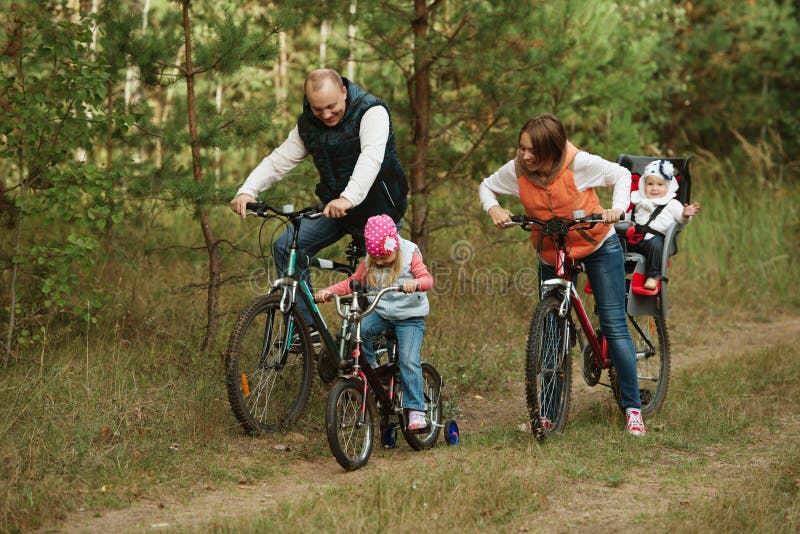 Happy family riding bike in wood