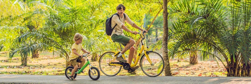 Happy family is riding bikes outdoors and smiling. Father on a bike and son on a balancebike BANNER, long format royalty free stock images Happy family is riding bikes outdoors and smiling. Father on a bike and son on a balancebike BANNER, long format royalty free stock images