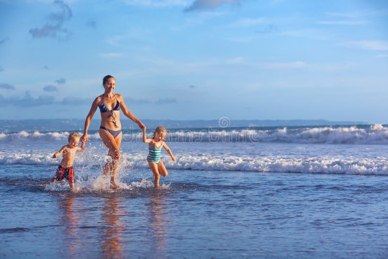 Happy family run with fun along sunset beach surf