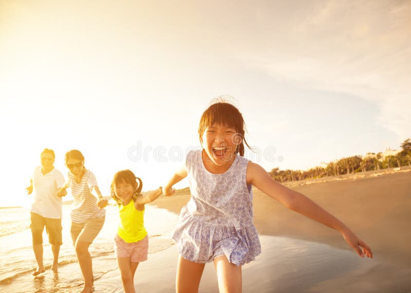 Felice asiatici famiglia in esecuzione sulla spiaggia.