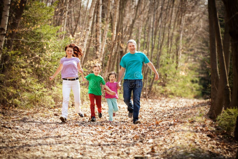 Happy family holding hands and having a fun time running along a path in the forest. Happy family holding hands and having a fun time running along a path in the forest.