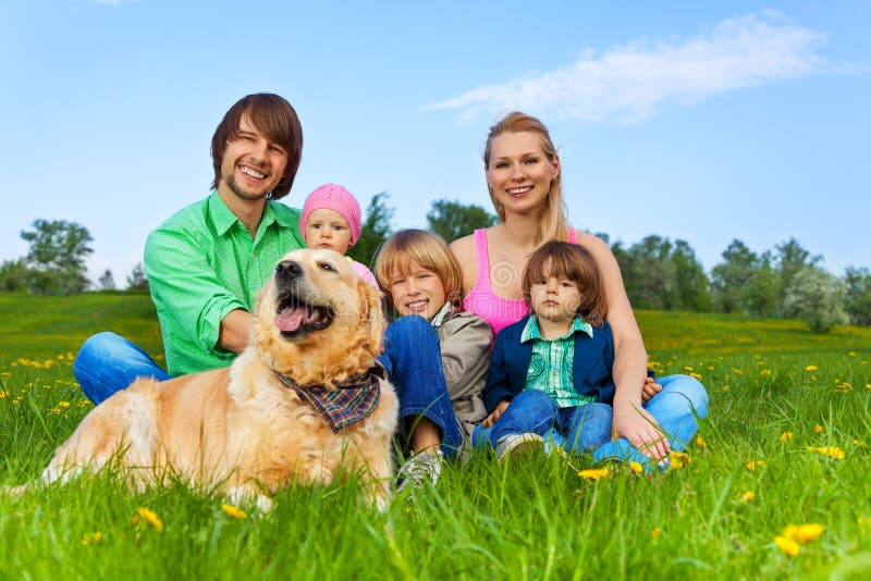 Happy family sitting on green grass in park with dog in summer. Happy family sitting on green grass in park with dog in summer