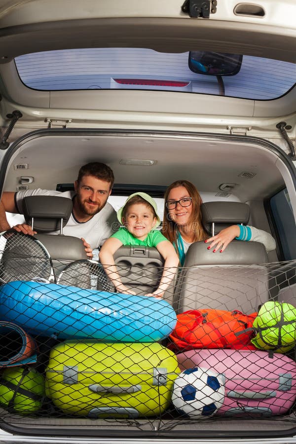 Happy family sitting in a minivan full of luggage