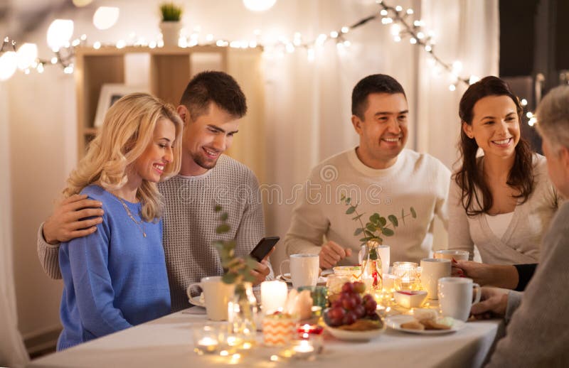 Happy family with smartphone at tea party at home stock photo Happy family with smartphone at tea party at home stock photo