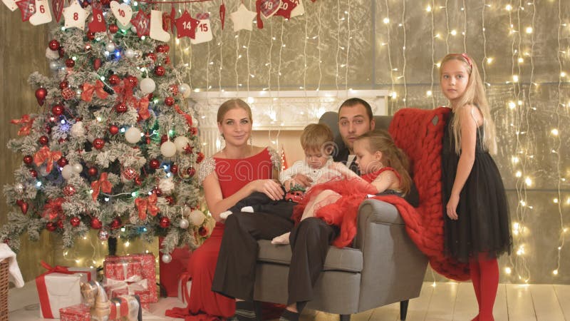 Happy family with three children sitting by the Christmas tree