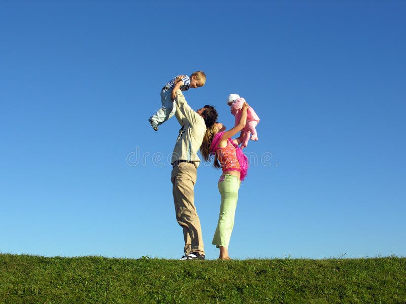 Familia feliz dos sobre el cielo azul césped verde.