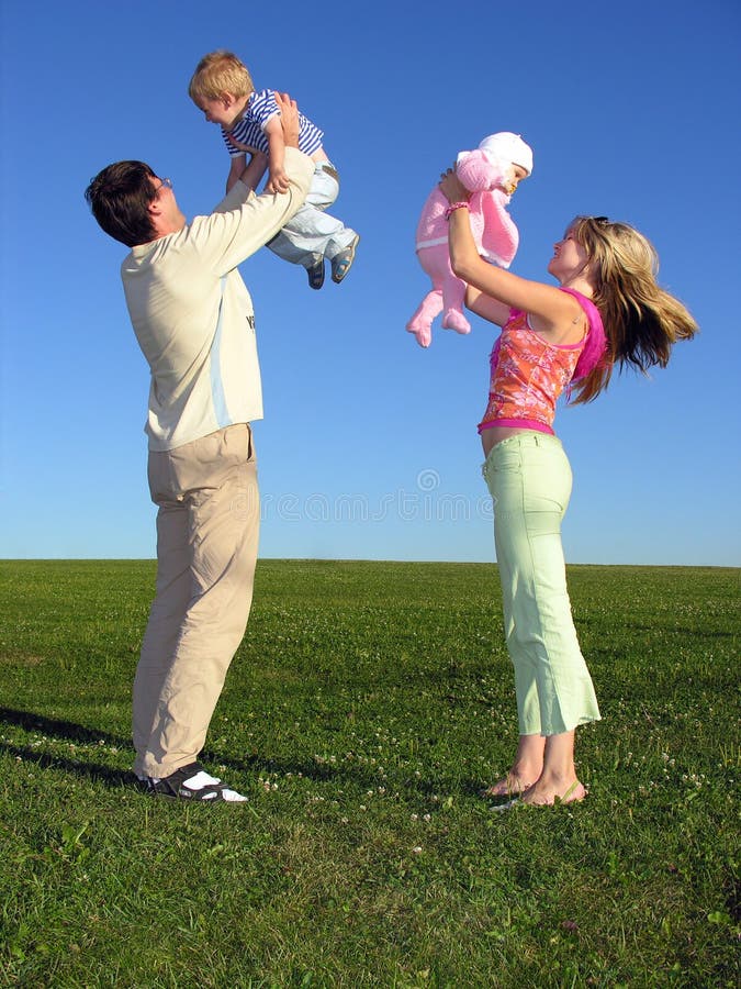 Glückliche Familie mit zwei Kindern auf blauen Himmel 3 grüne gras.