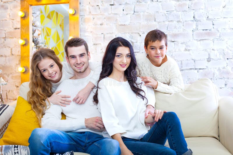 Happy family with two children boy and girl sitting on couch in light blouses and blue jeans. Christmas. stock photos Happy family with two children boy and girl sitting on couch in light blouses and blue jeans. Christmas. stock photos
