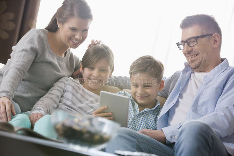 Happy family using digital tablet together in living room