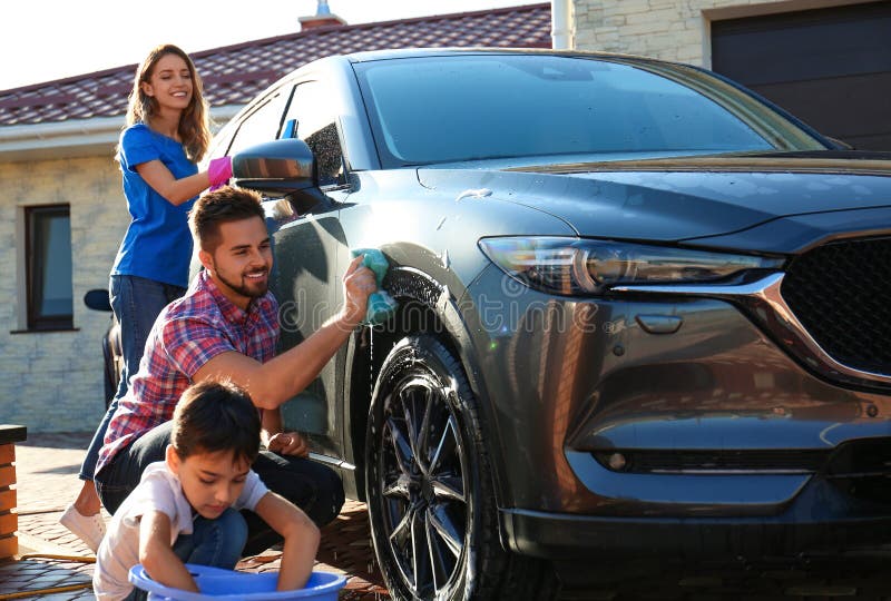 Happy family washing car at backyard on sunny day