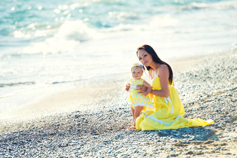 Happy family in a yellow dress. Mother and child are walking on the beach royalty free stock image Happy family in a yellow dress. Mother and child are walking on the beach royalty free stock image