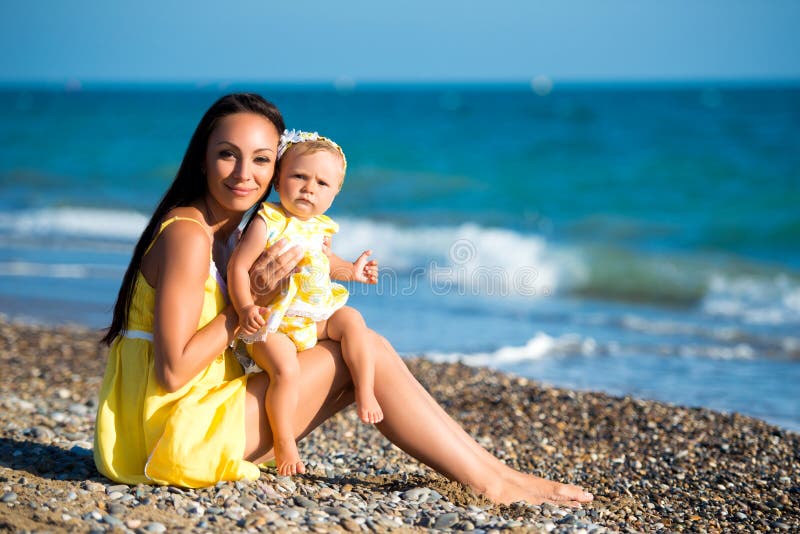 Happy family in a yellow dress. Mother and child are walking on the beach stock photography Happy family in a yellow dress. Mother and child are walking on the beach stock photography
