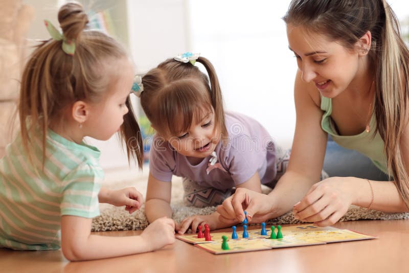 Happy family. Young mother playing ludo boardgame with her daughters while spending time together at home.