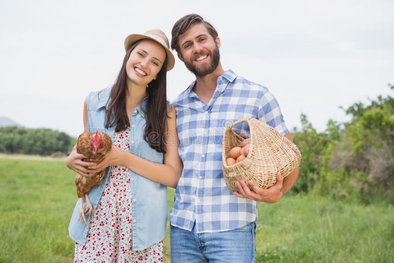 Happy farmers holding chicken and eggs. 