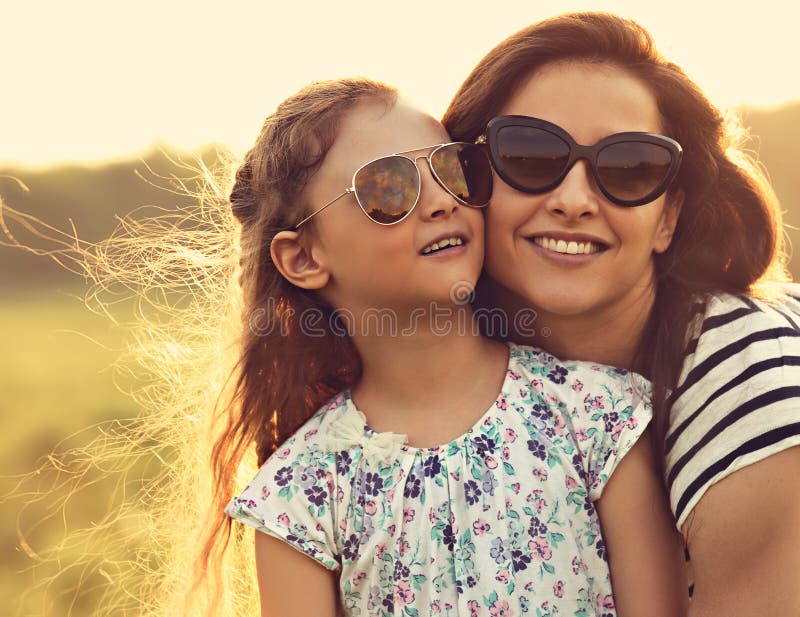 Happy fashion kid girl embracing her mother in trendy sunglasses