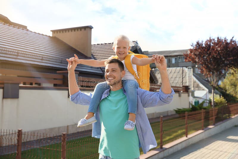Happy father carrying his little child with school bag on shoulders royalty free stock photography Happy father carrying his little child with school bag on shoulders royalty free stock photography