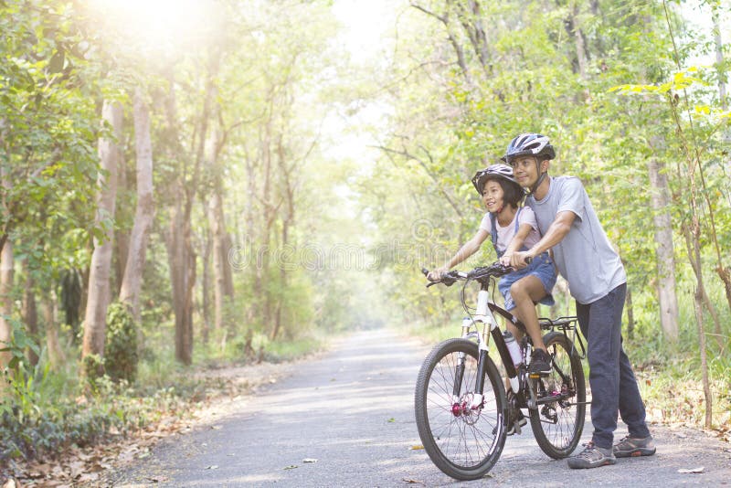 Happy father and daughter cycling in the park