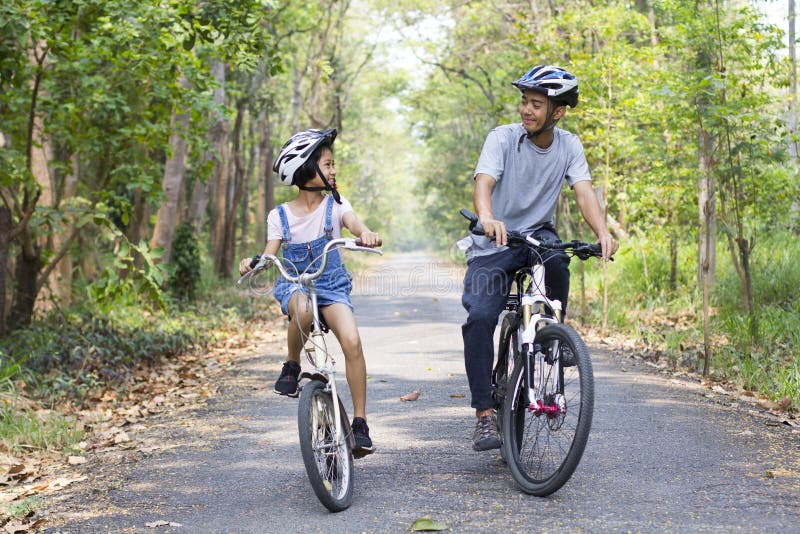 Happy father and daughter cycling in the park