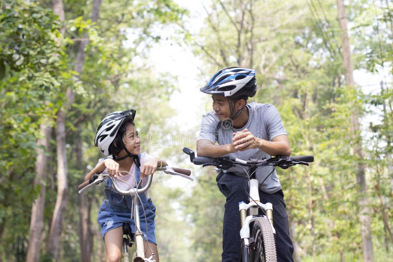 Happy father and daughter cycling in the park