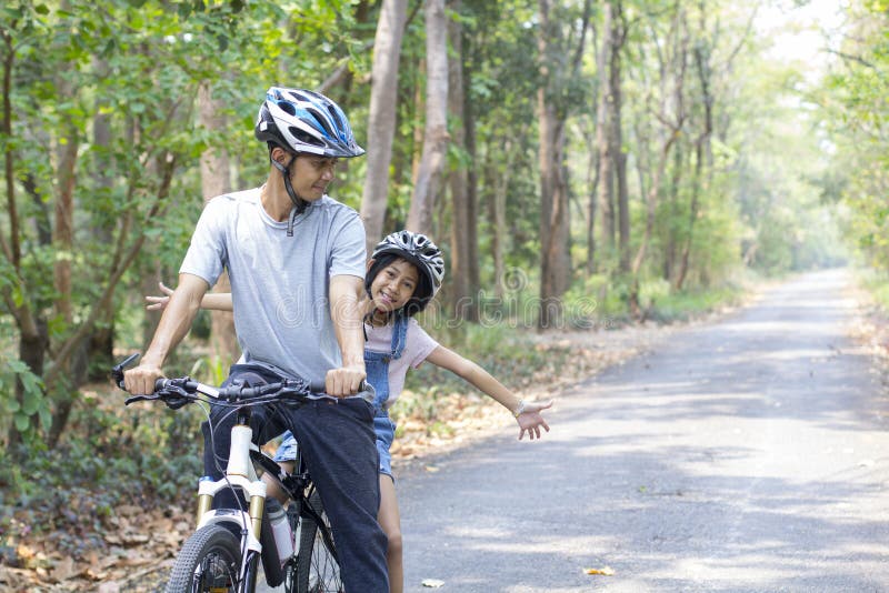 Happy father and daughter cycling in the park