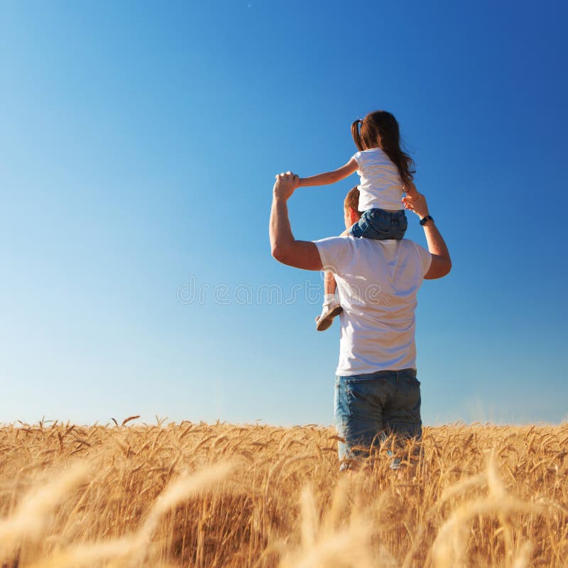 Happy father and daughter walk in the summer field. Nature beauty, blue sky and field with golden wheat. Outdoor lifestyle. stock image Happy father and daughter walk in the summer field. Nature beauty, blue sky and field with golden wheat. Outdoor lifestyle. stock image