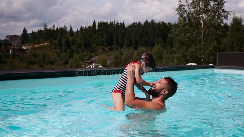 Father kissing her daughter while lifting her in swimming pool