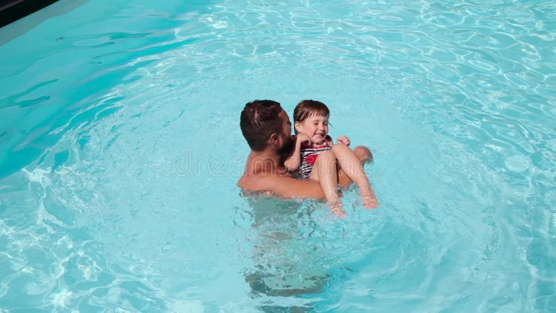 Happy father playing with daughter in swimming pool