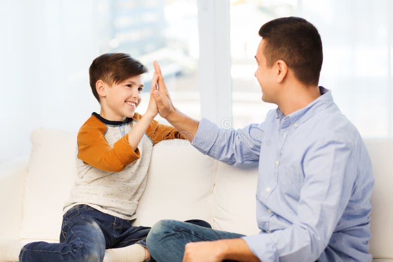 Happy father and son doing high five at home stock images Happy father and son doing high five at home stock images