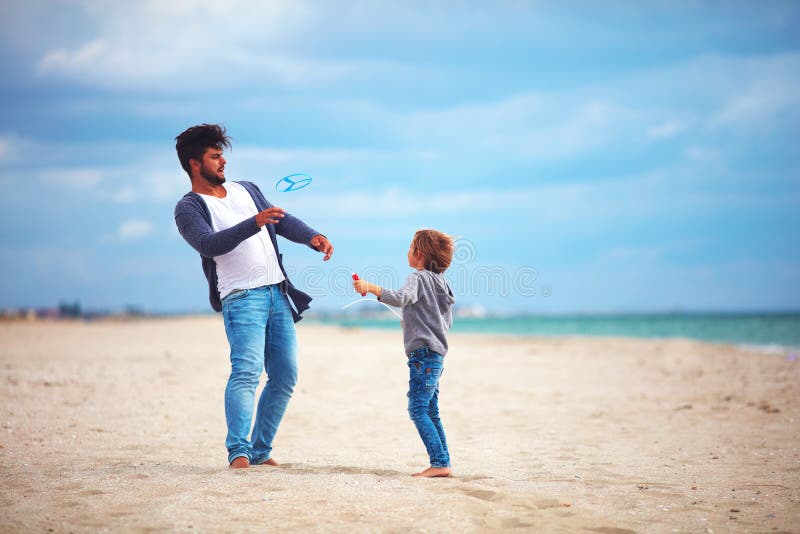 Happy father and son having fun on the beach, playing summer activity games, launching propeller toy in the air royalty free stock photo Happy father and son having fun on the beach, playing summer activity games, launching propeller toy in the air royalty free stock photo