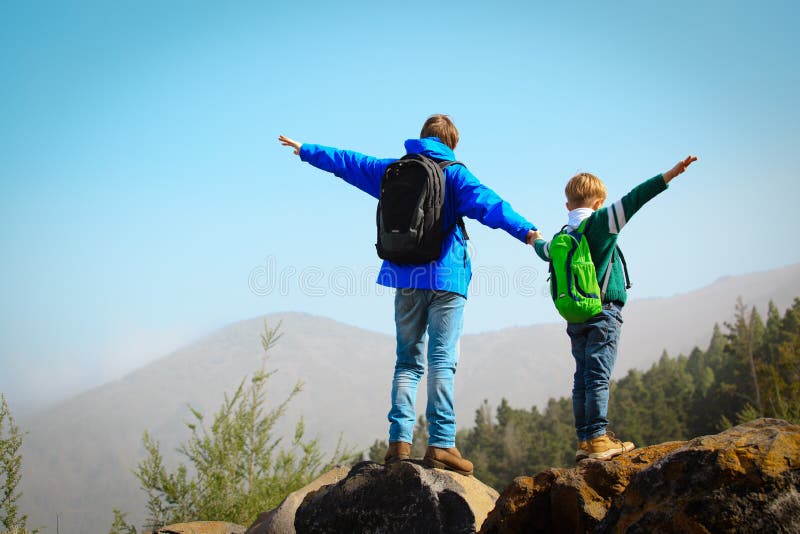 Happy father and son hiking climbing in mountains stock images