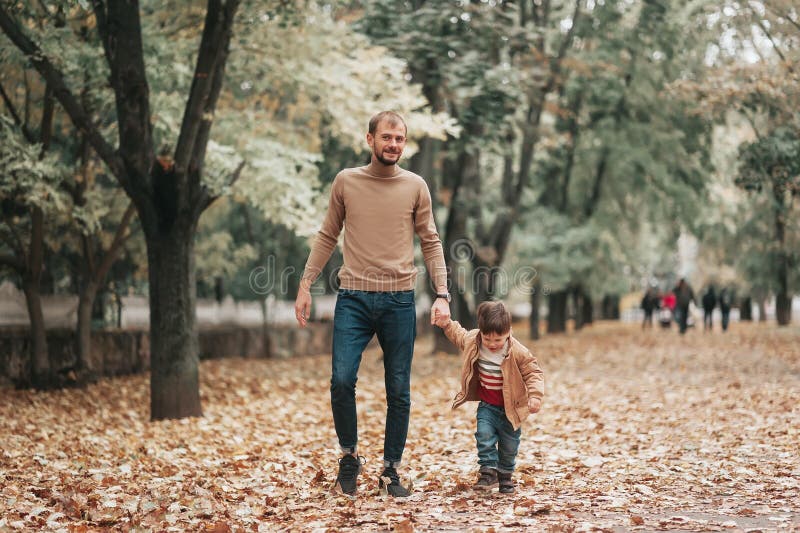 The Dad Social Happy Father and Son Holding Hands while Walking in Park. Relationship