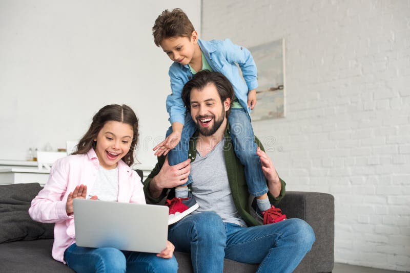 happy father with two cute kids sitting on sofa and using laptop stock photos happy father with two cute kids sitting on sofa and using laptop stock photos