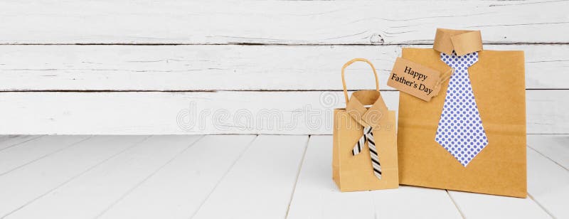 Happy Fathers Day card and shirt and tie gift bags. Side view on a white wood banner background. Happy Fathers Day card and shirt and tie gift bags. Side view on a white wood banner background