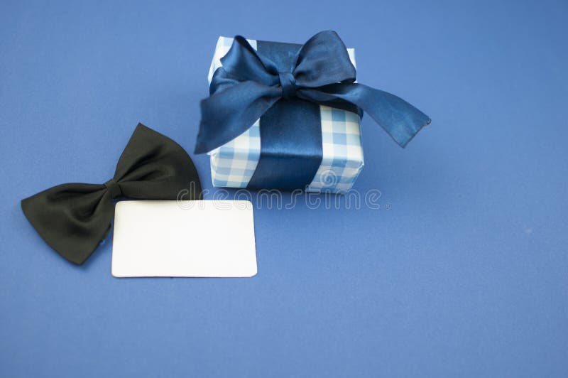 Happy Fathers day concept. Gift box with bow tie and blank tag over dark blue paper background. Top view. International men`s day royalty free stock image Happy Fathers day concept. Gift box with bow tie and blank tag over dark blue paper background. Top view. International men`s day royalty free stock image