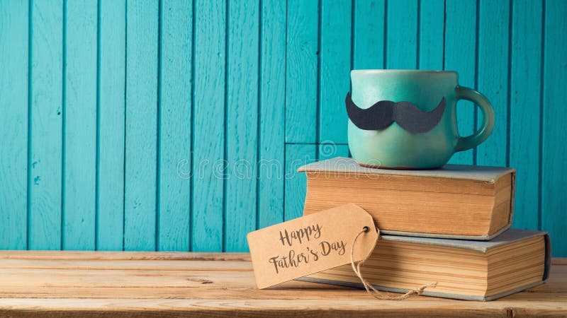 Happy Fathers day concept with coffee cup, mustache and books over wooden background