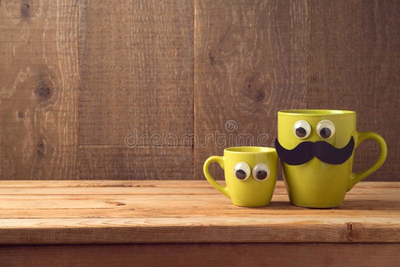 Happy Fathers day concept with two coffee cups as father and son over wooden background