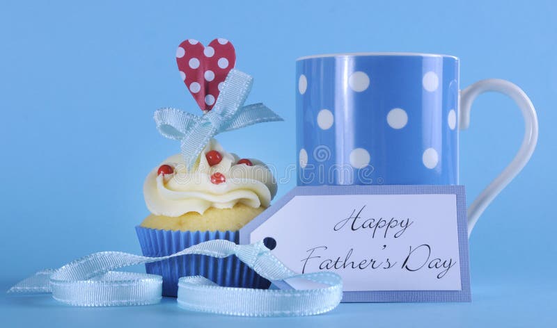 Happy Fathers Day cupcake with red and white decorations with polka dot coffee mug and greeting gift tag on pale blue background. Happy Fathers Day cupcake with red and white decorations with polka dot coffee mug and greeting gift tag on pale blue background.