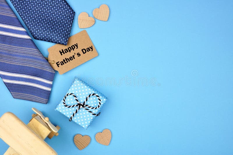 Happy Fathers Day gift tag with side border of gifts, ties and hearts on a blue background. Top view with copy space
