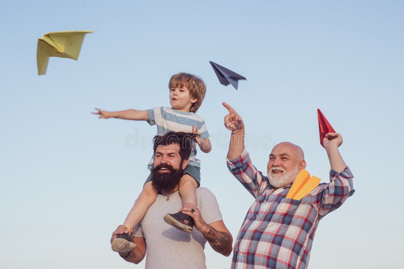 Happy fathers day. Happy grandfather father and grandson with toy paper airplane over blue sky and clouds background royalty free stock photo Happy fathers day. Happy grandfather father and grandson with toy paper airplane over blue sky and clouds background royalty free stock photo