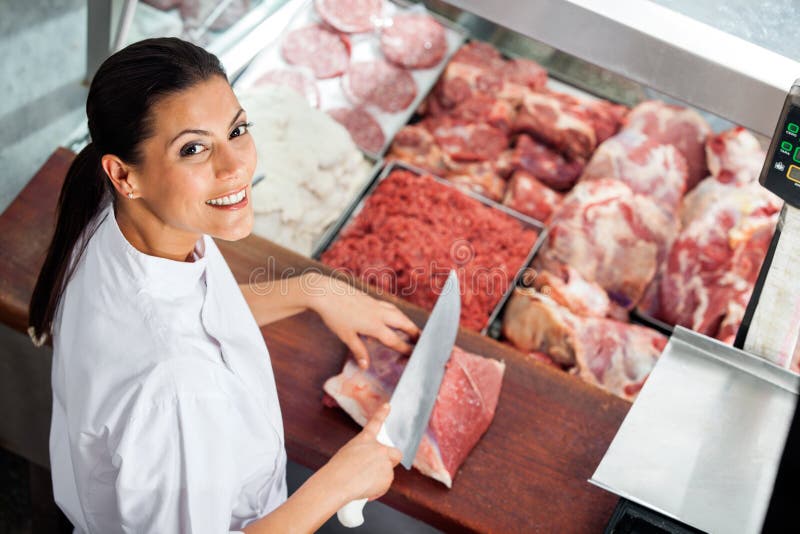 Happy Female Butcher Cutting Meat At Butchery