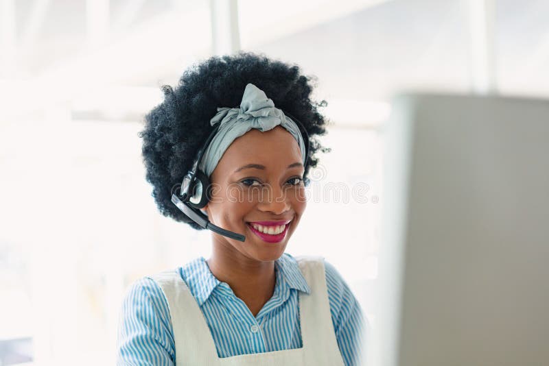 Portrait of happy mixed-race female customer service executive talking on headset in office. New start-up business with entrepreneur working hard. Portrait of happy mixed-race female customer service executive talking on headset in office. New start-up business with entrepreneur working hard