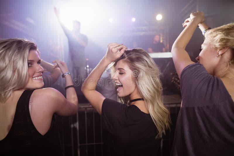Happy female friends dancing at nightclub