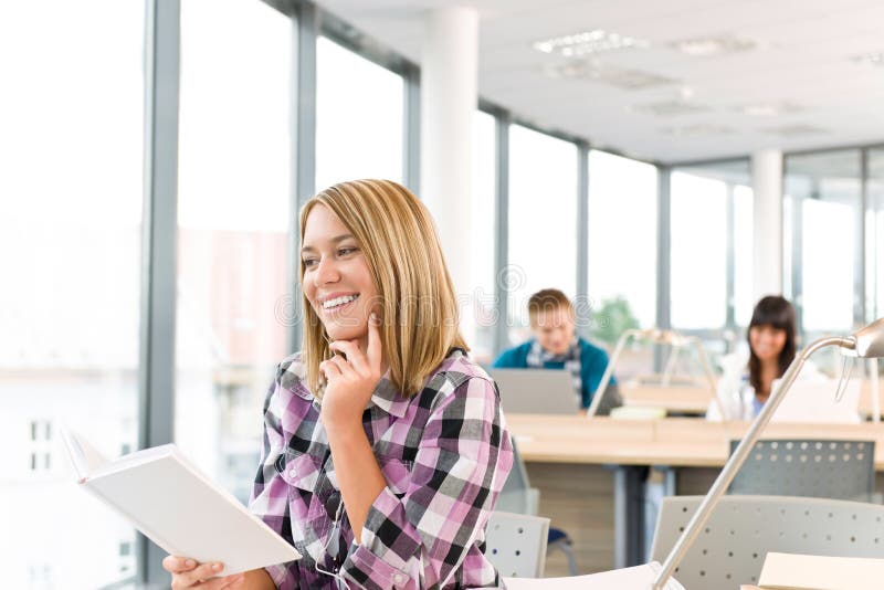Happy female student with book in classroom royalty free stock photography