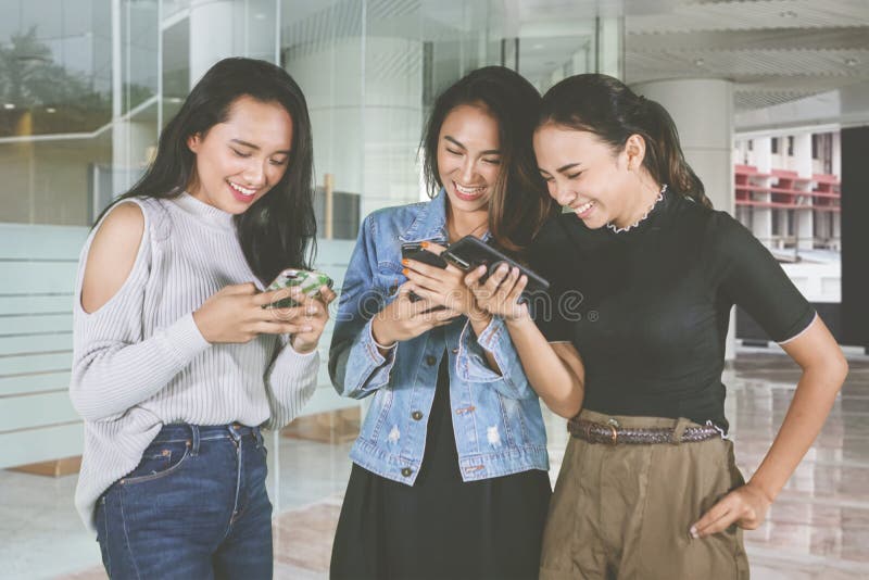 Happy female teenagers using phone at outdoors