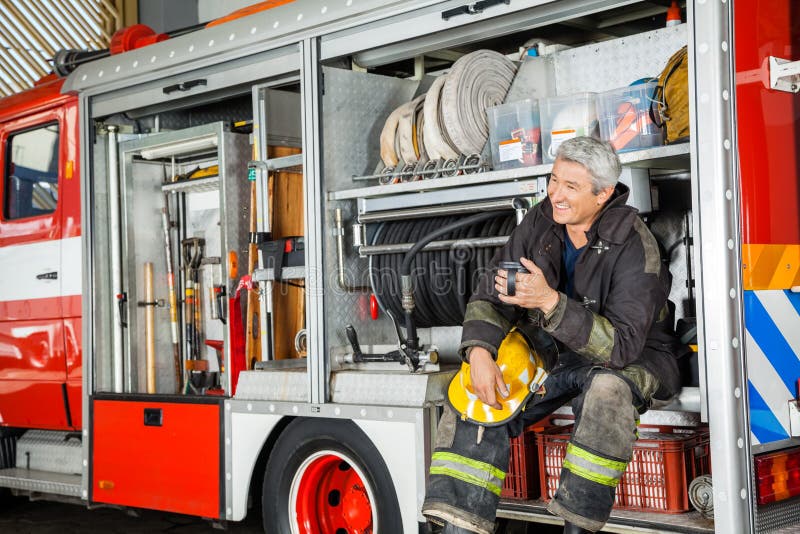 Happy Fireman Sitting In Truck At Fire Station stock photos